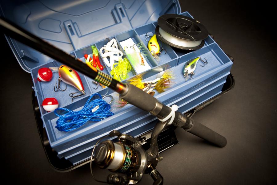 fishing pole situated next to a tackle box full of fishing equipment