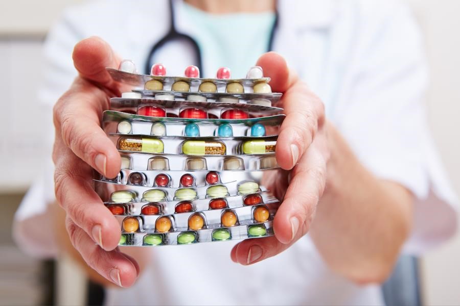 A pharmacist holding several pill packets.