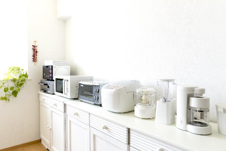 Microwaves, blenders, food processors, and other kitchen appliances crammed on a kitchen counter.
