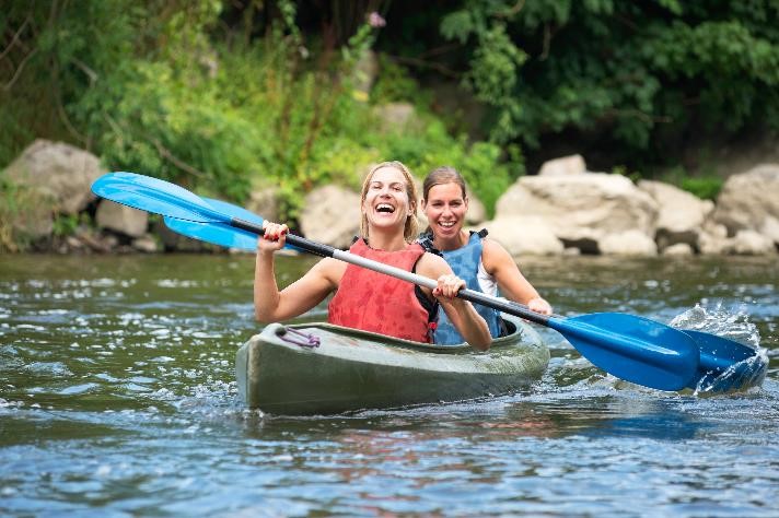Two smiling women paddling in a kayak.