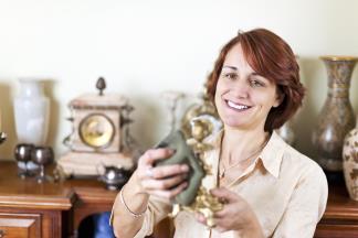 woman smiling while cleaning off home decor with a towel