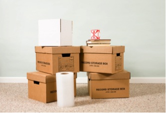 five boxes stacked upon each other with a roll of toilet paper and two books situated on top