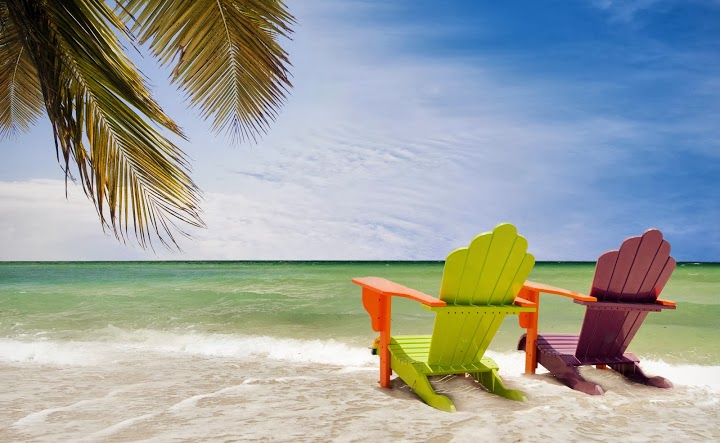 two beach lounge chairs on a beach shore