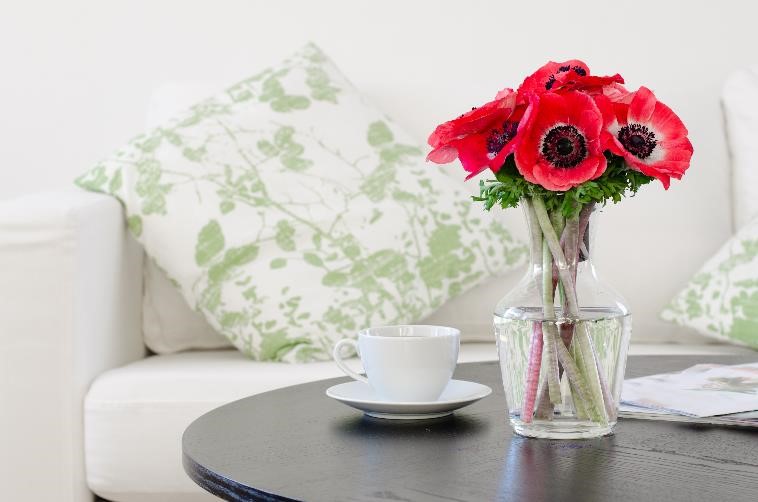 coffee table with a tea cup and vase situated on top, with white couch in background