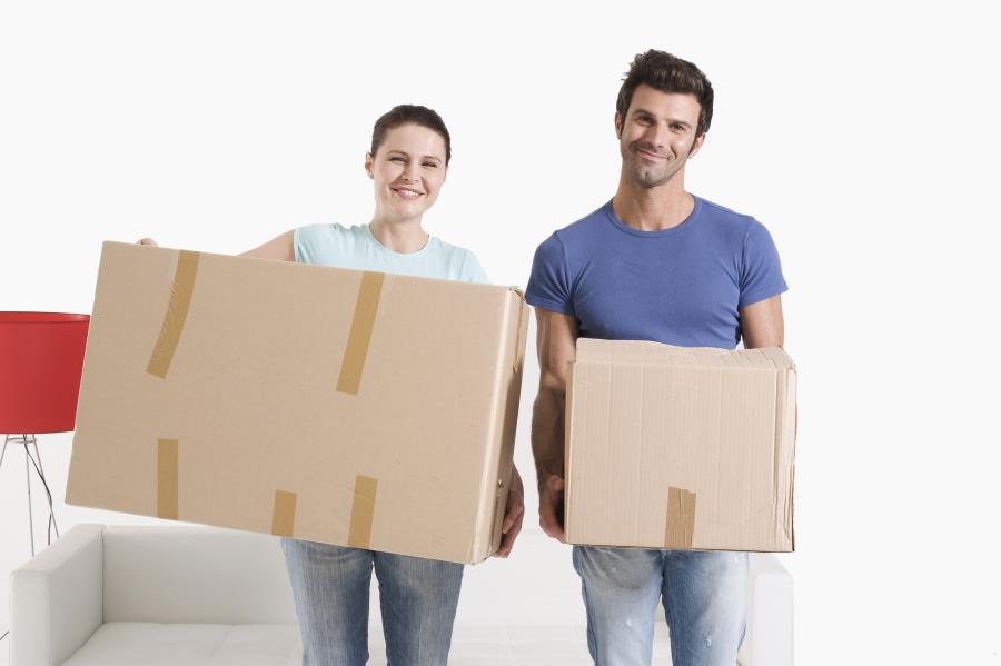 man and woman smiling while holding cardboard boxes