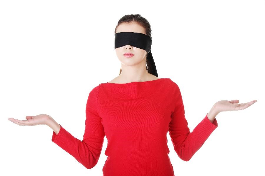 A blindfolded woman shrugging her shoulders with her palms facing upward.