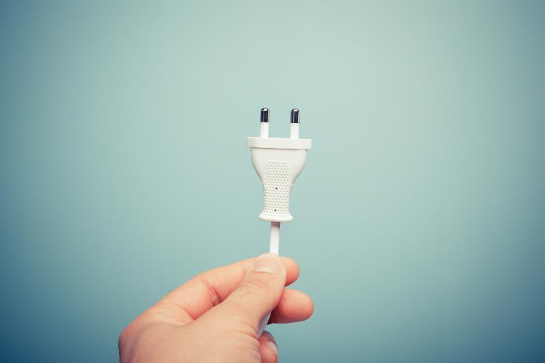 A person holding up a electircal plug-in cord.