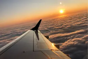 The view from a plane window with a plane wing and sunset.