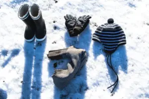 Winter clothes and shoes sitting on a snowy ground.